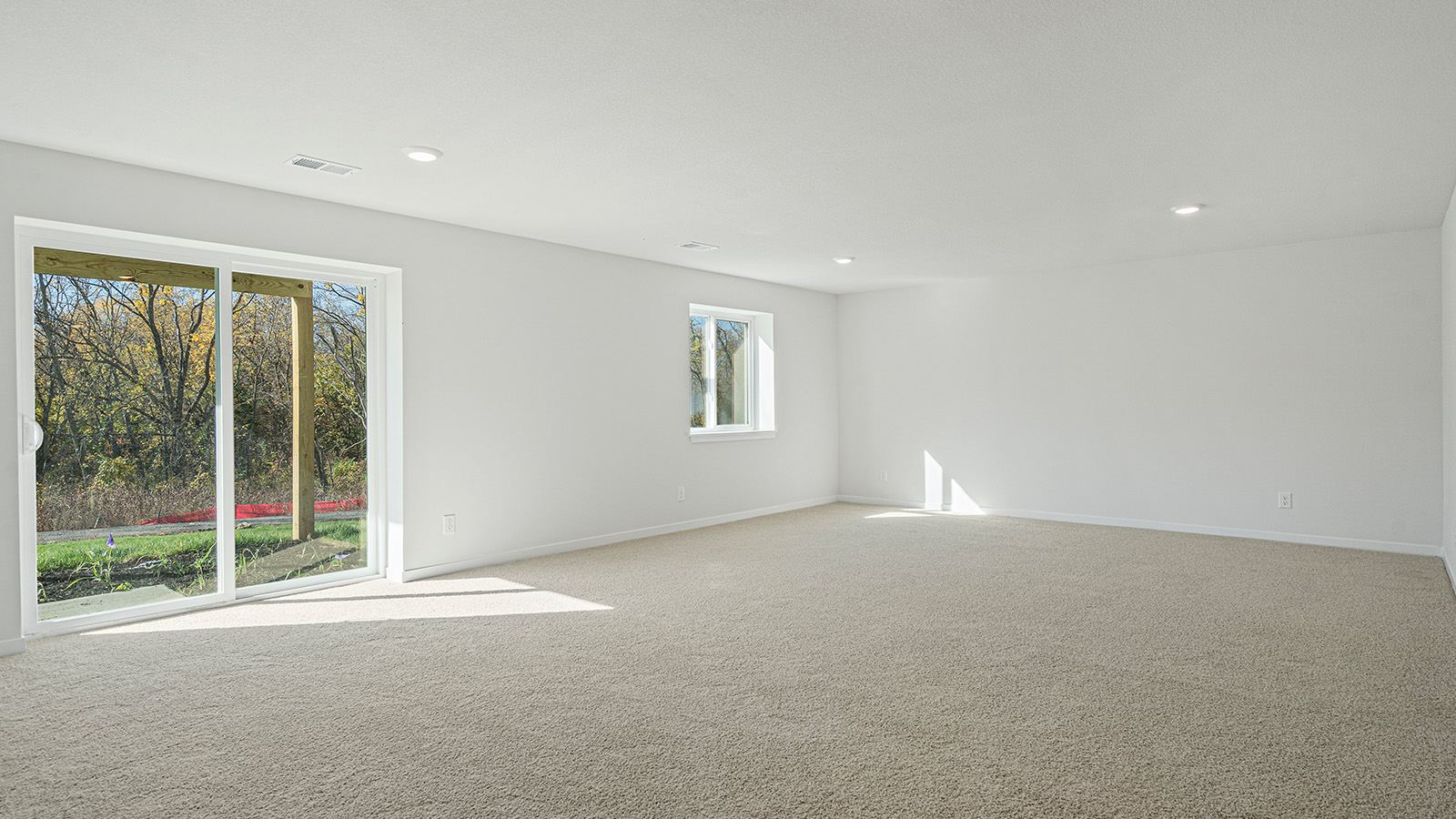 Large open concept carpeted basement with large windows