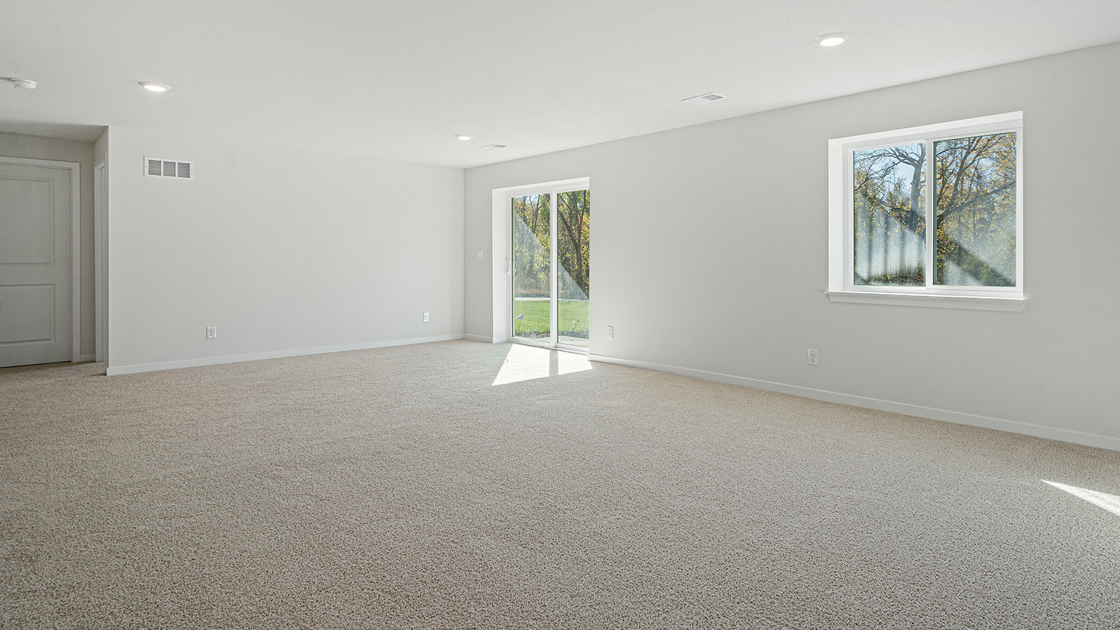 Large open concept carpeted basement with large windows