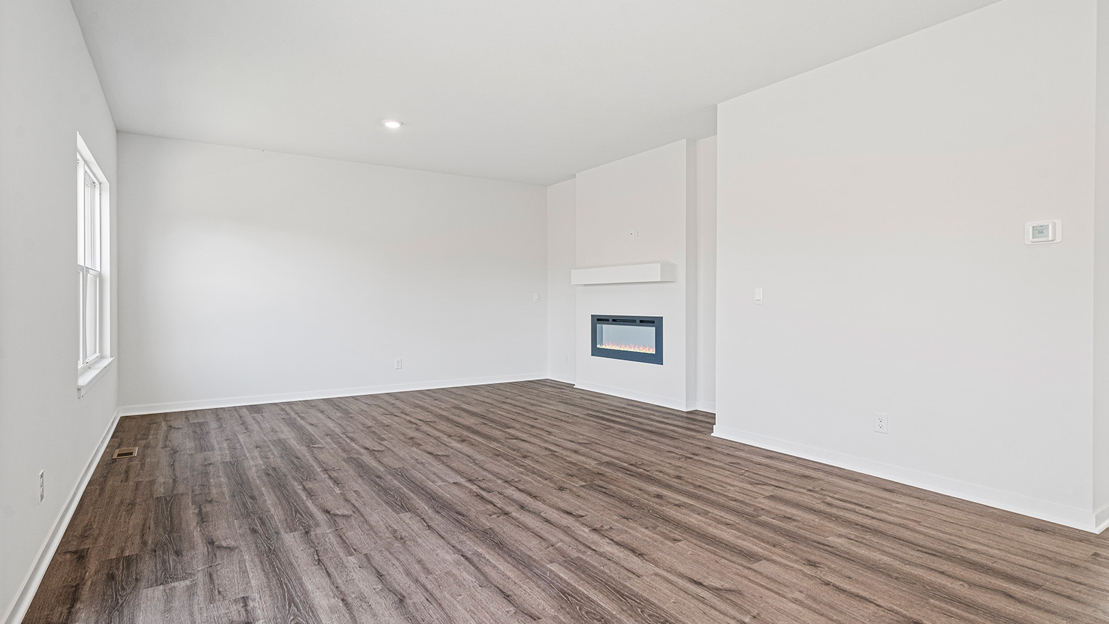 Living room beside kitchen, with electric fireplace and large windows