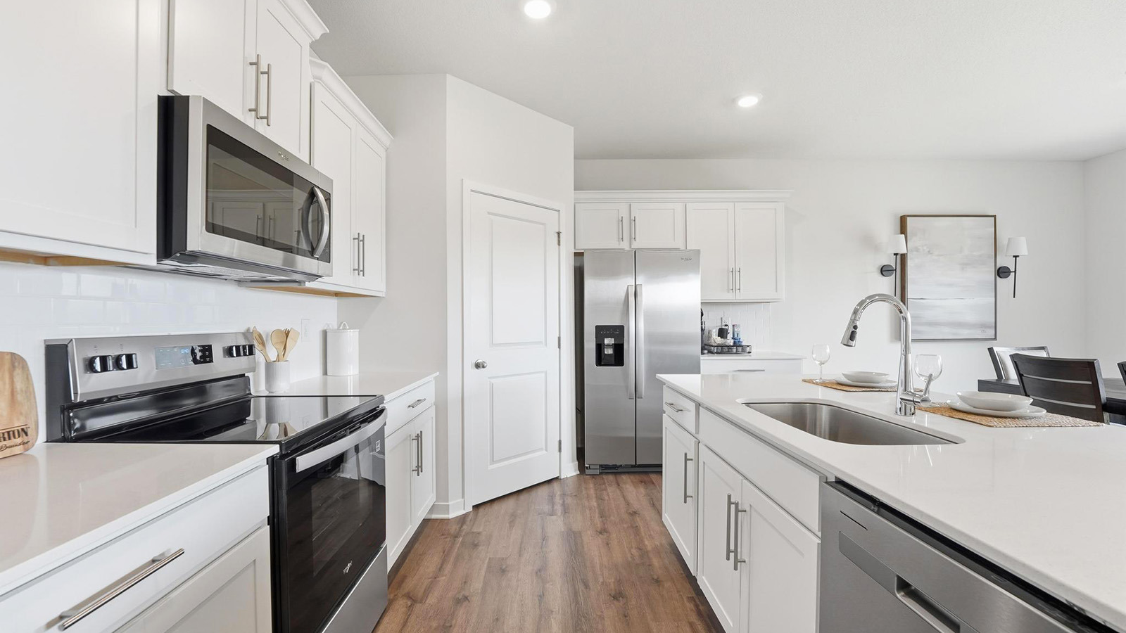 Kitchen and island with white cabinets, tile backsplash, and stainless steel appliances