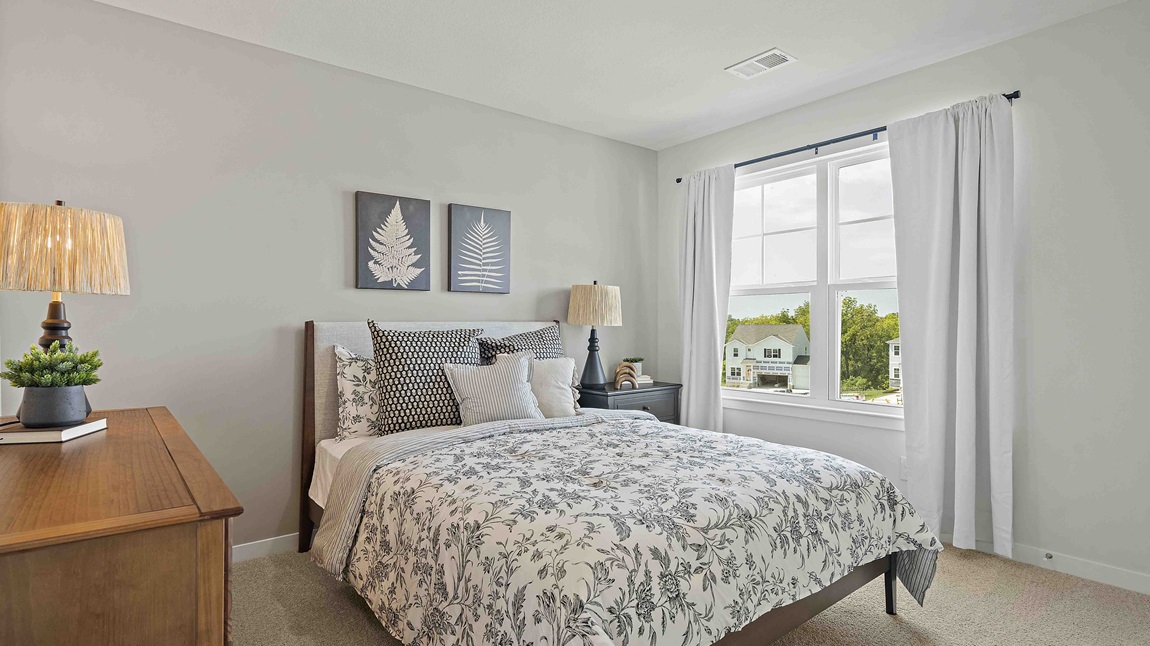 Carpeted bedroom with large window.