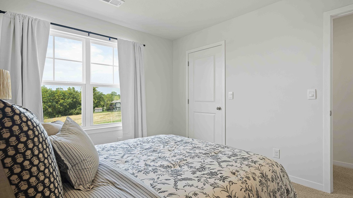 Carpeted bedroom with large window.