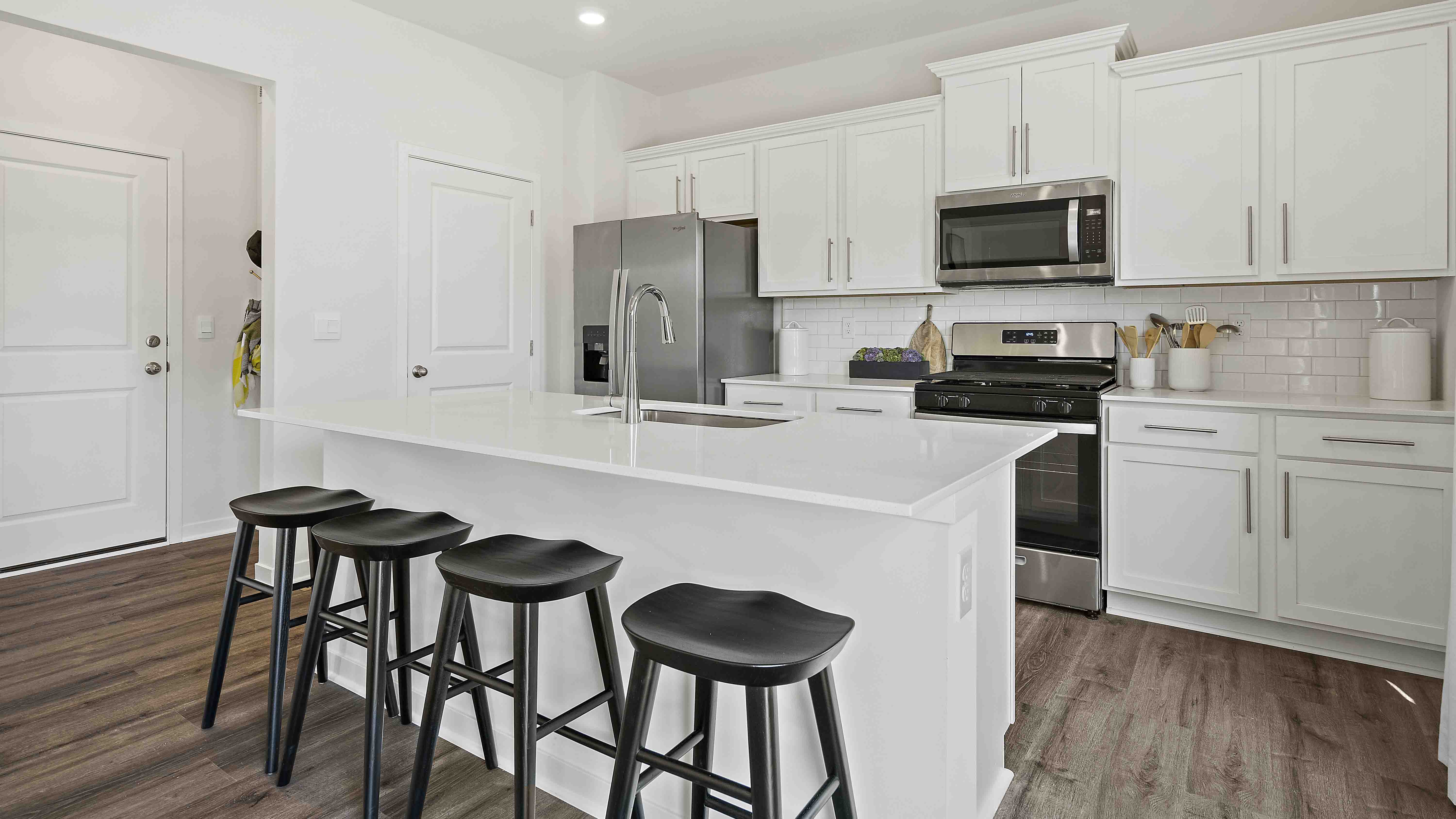 Kitchen and island with white cabinets and stainless steel appliances.