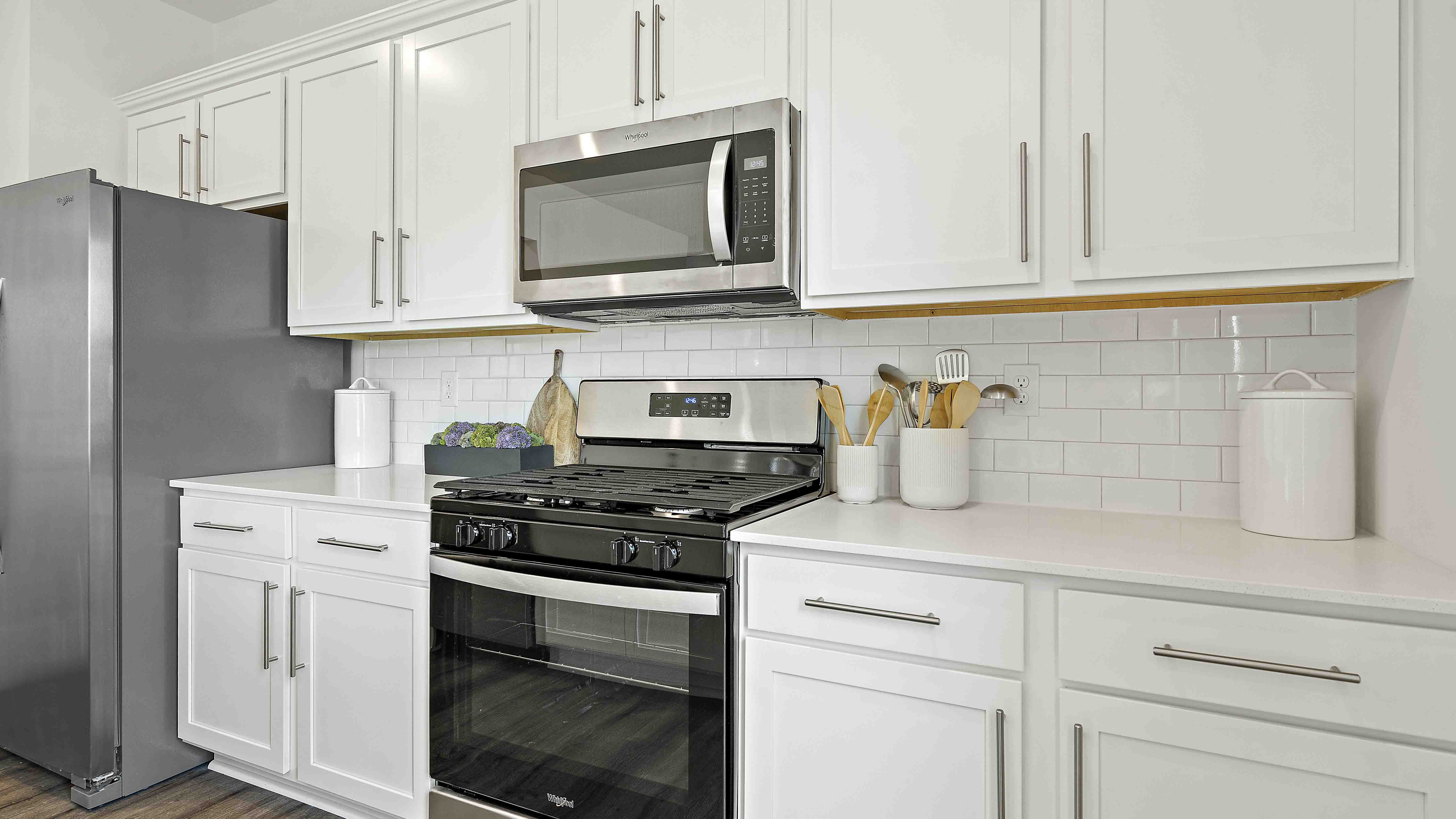 Kitchen and island with white cabinets and stainless steel appliances.