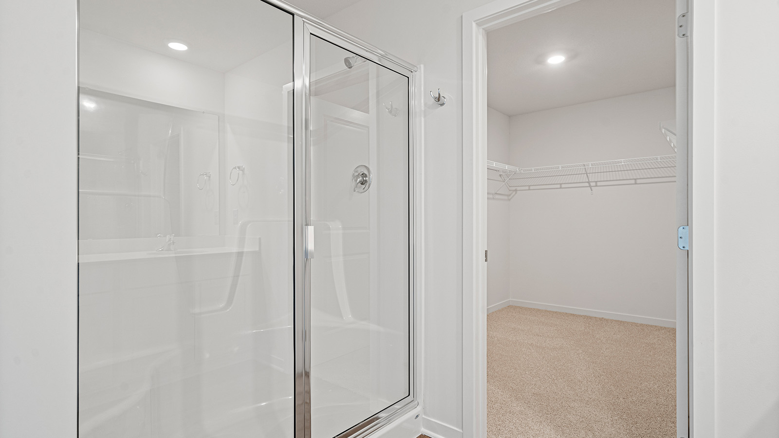Primary bathroom with double sinks, white cabinets, and glass shower.