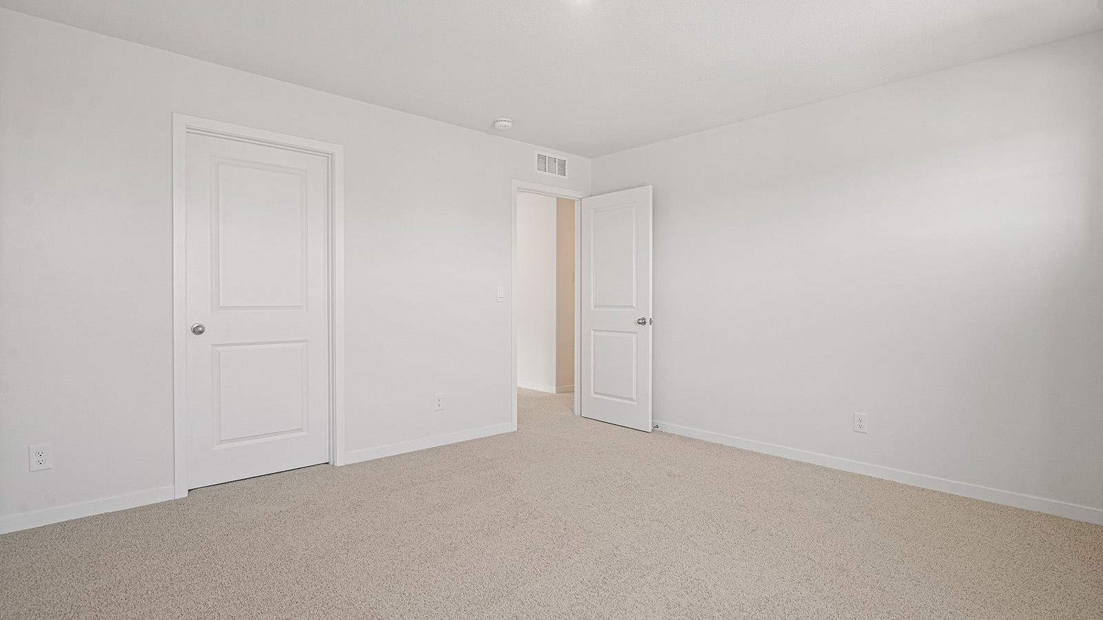 Carpeted bedroom with small window.
