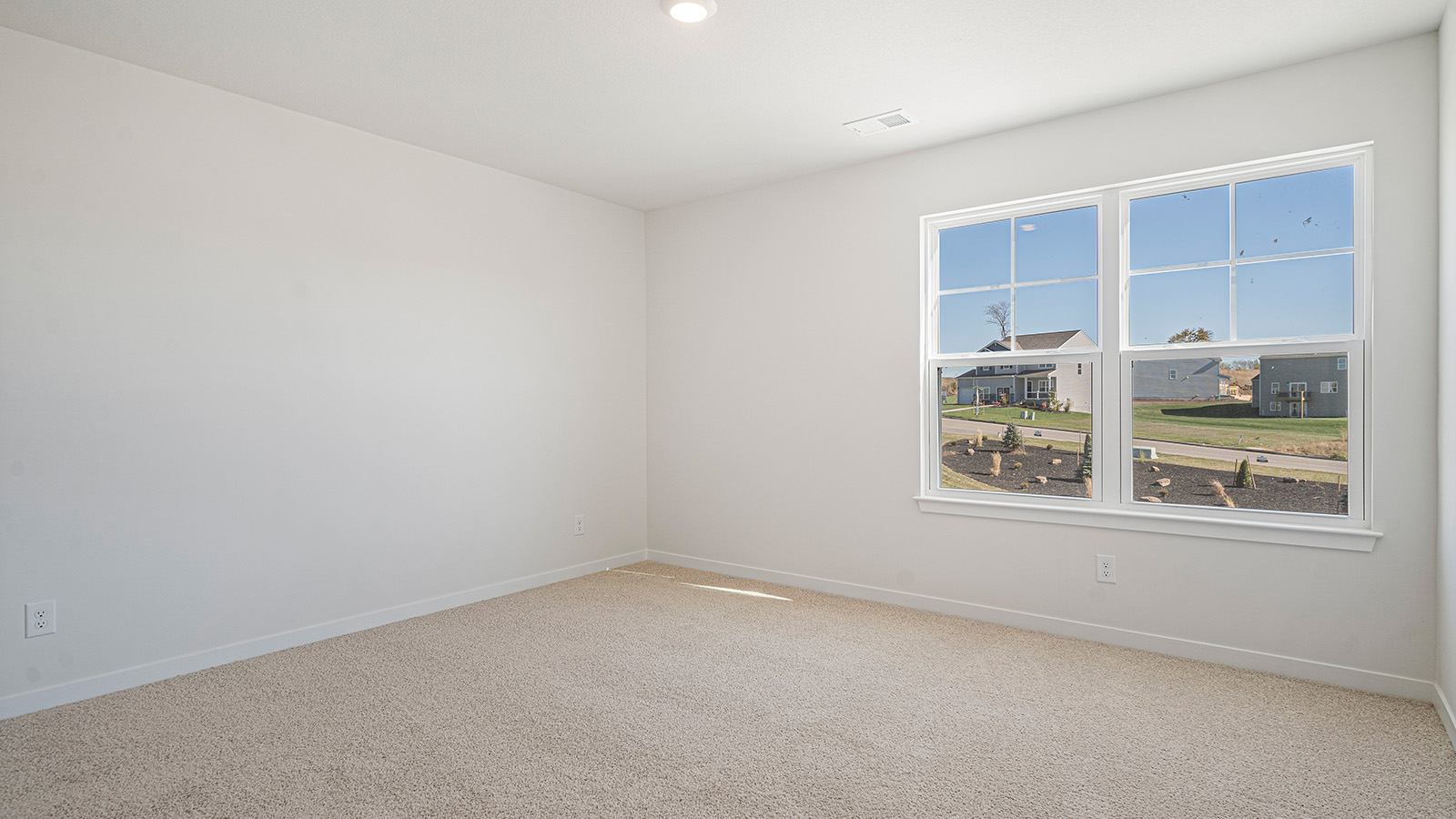 Carpeted bedroom with small window.