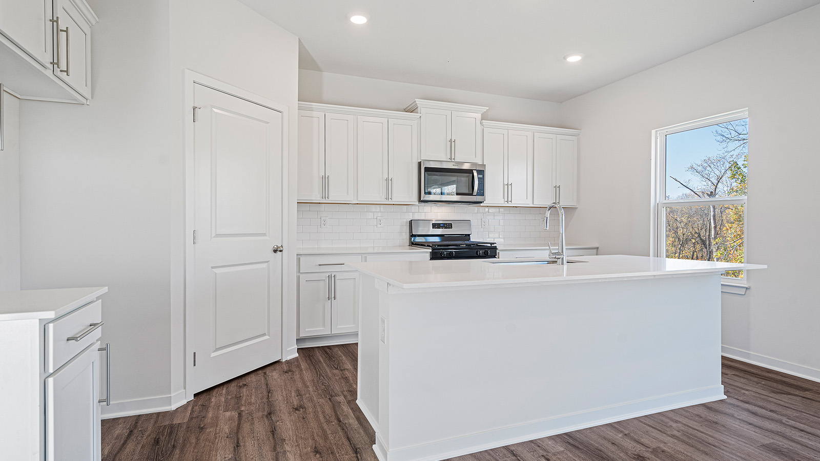 Kitchen with large island, white cabinets and countertops and stainless steel appliances