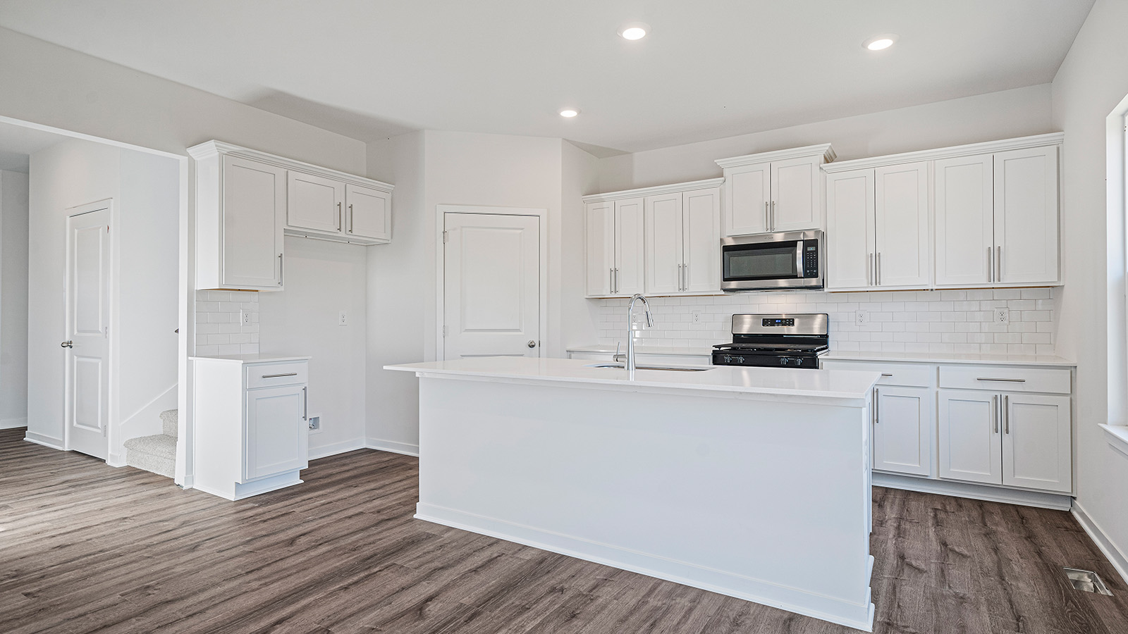 Kitchen with large island, white cabinets and countertops and stainless steel appliances