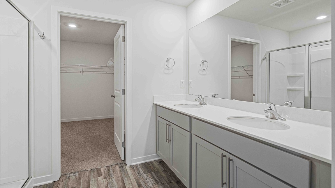 Primary bathroom with gray cabinets, double sink vanity, and standing glass door shower