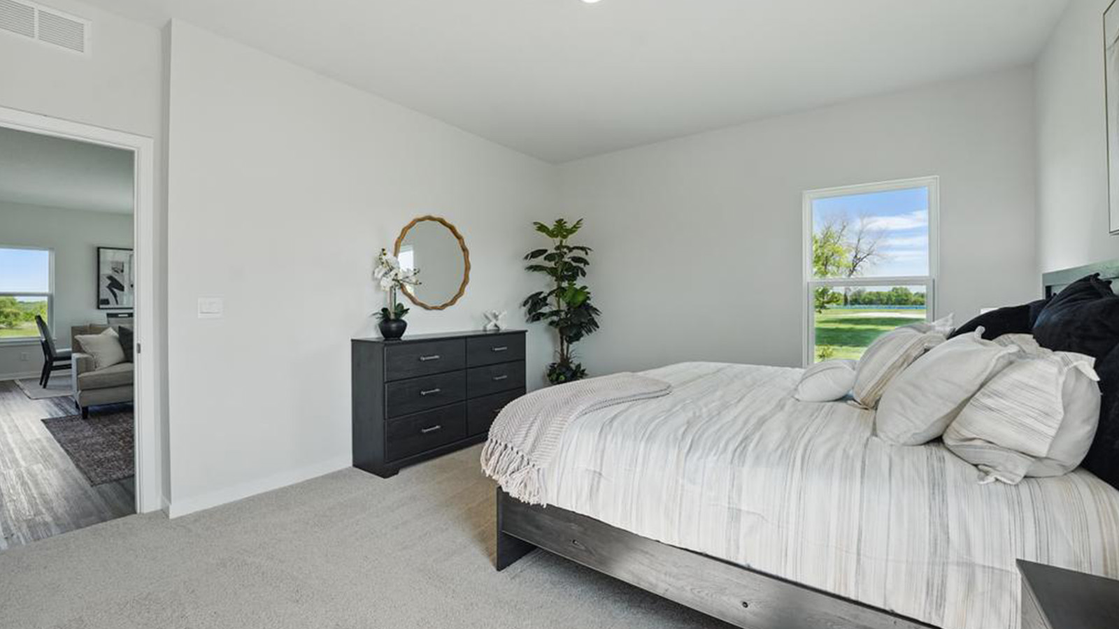 Primary bedroom with carpet and large window.