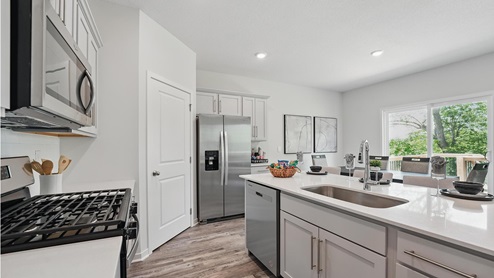 Kitchen and island with gray cabinets and stainless steel appliances. New Homes in Kansas City, Missouri