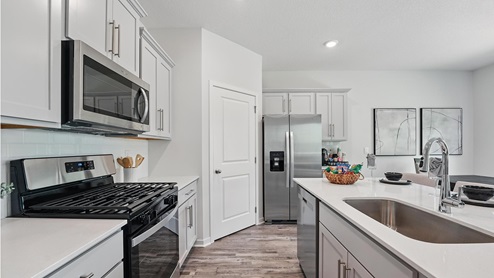 Kitchen and island with gray cabinets and stainless steel appliances. New Homes in Kansas City, Missouri