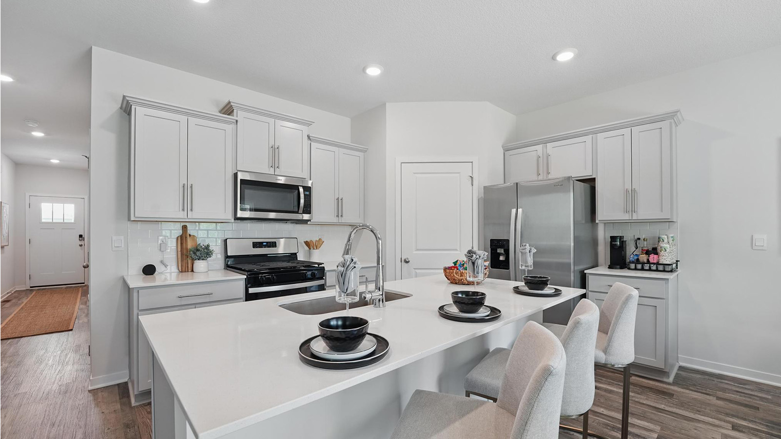 Kitchen and island with gray cabinets and stainless steel appliances. New Homes in Kansas City, Missouri