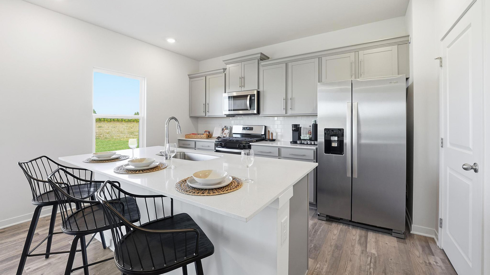 Kitchen and island with white cabinets and stainless steel appliances.