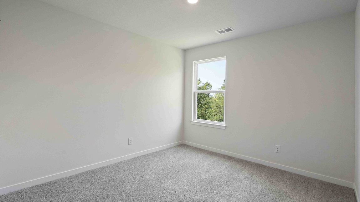 Carpeted bedroom with large window. New Homes in Kansas City, Missouri