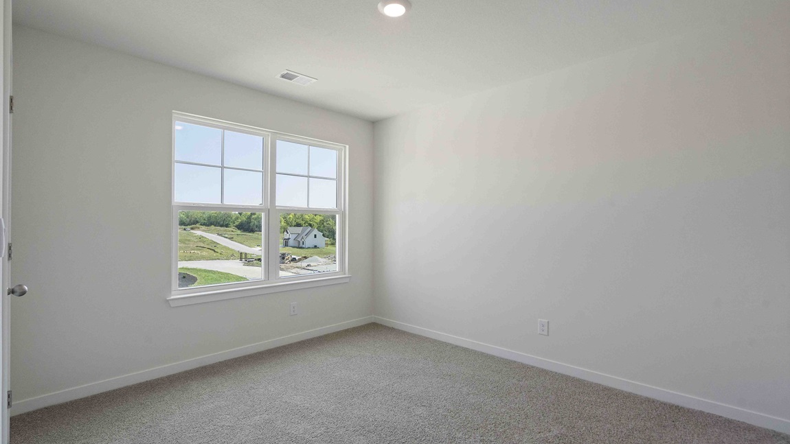 Carpeted bedroom with large window. New Homes in Kansas City, Missouri