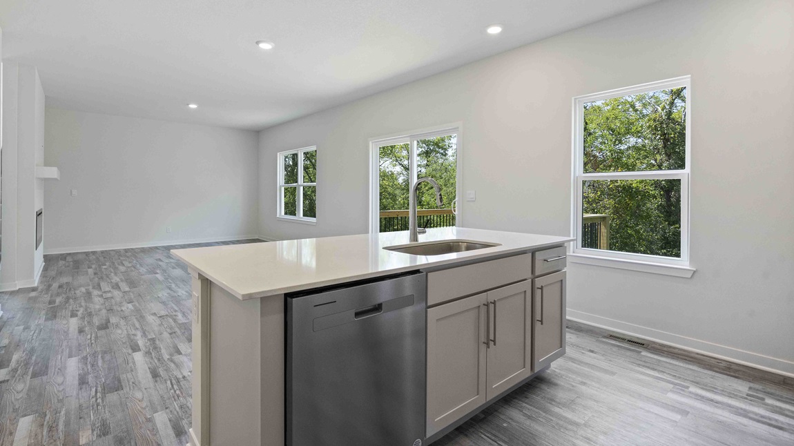 Kitchen and island with white cabinets and stainless steel appliances. New Homes in Kansas City, Missouri