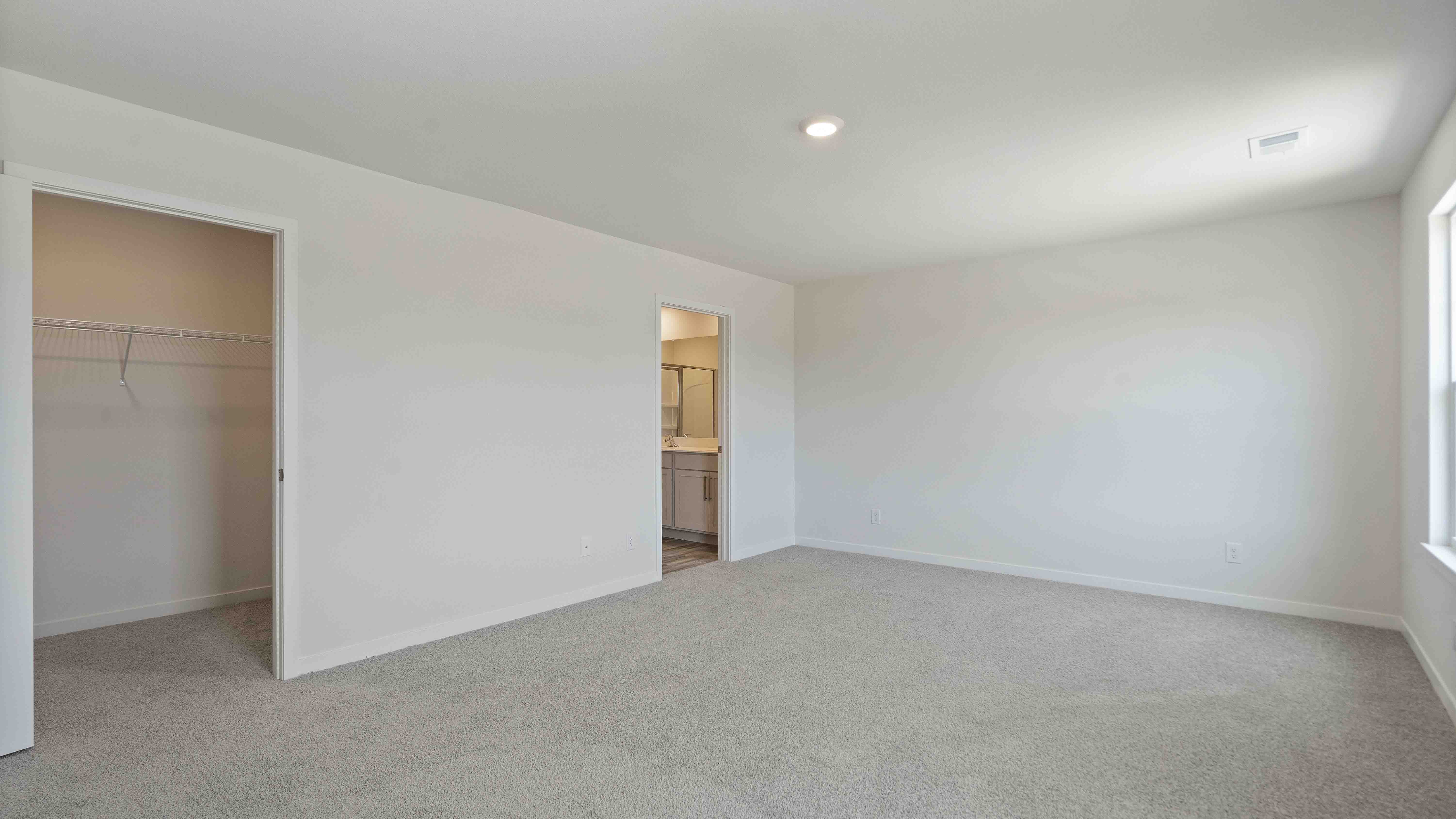 Carpeted primary bedroom with large windows and seating area. New Homes in Kansas City, Missouri