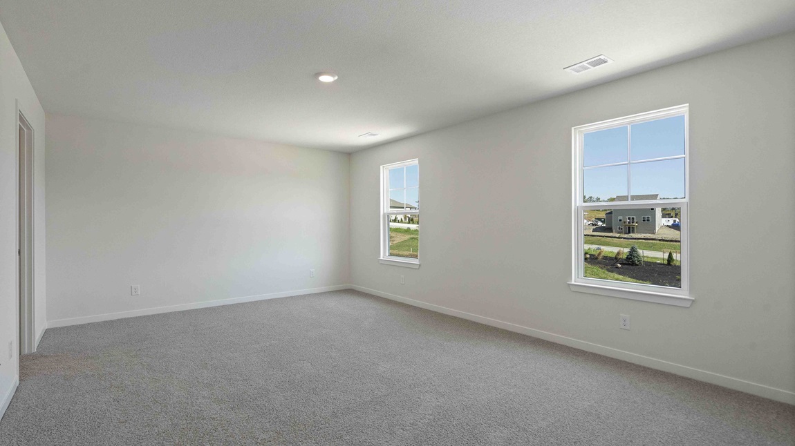 Carpeted primary bedroom with large windows and seating area. New Homes in Kansas City, Missouri