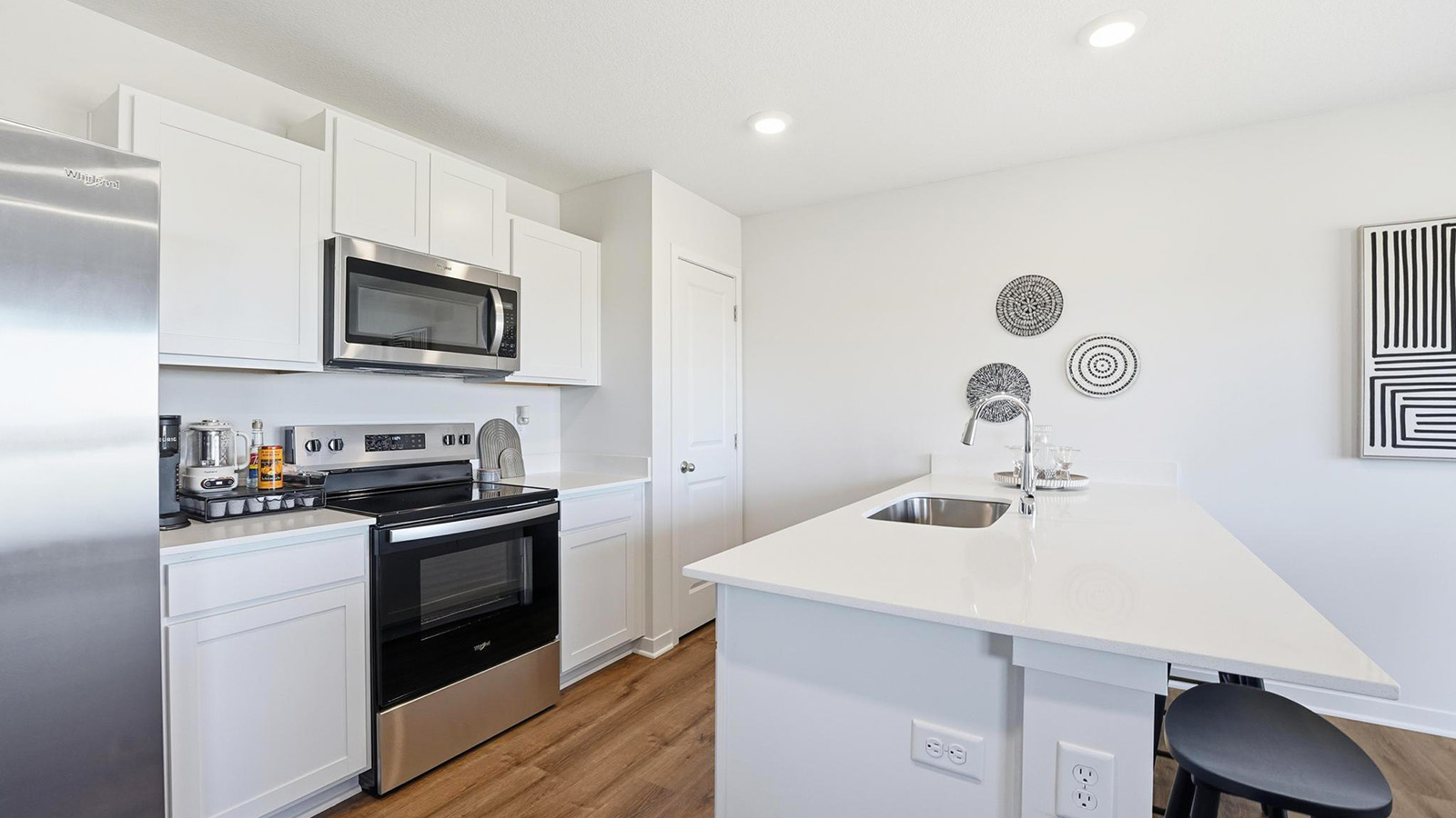 Open-concept kitchen with white quartz counters and cabinets, and stainless steel appliances