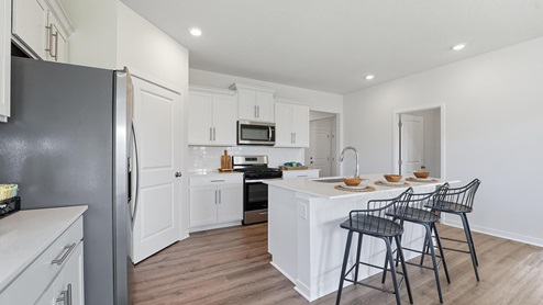 Kitchen and island with white cabinets, subway tile backsplash and stainless steel appliances