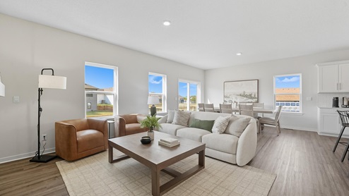 Living room with electric fireplace and two large windows, beside kitchen and dining area