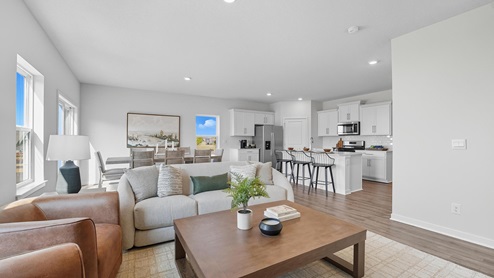Living room with electric fireplace and two large windows, beside kitchen and dining area