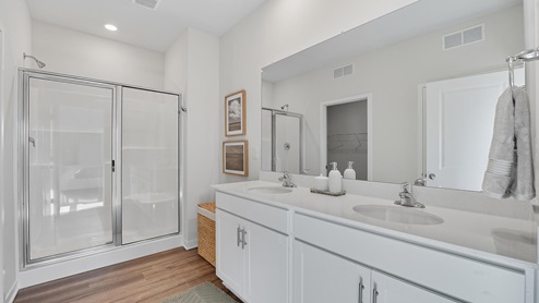 Pirmary bathroom with double sink vanity and standing glass door shower