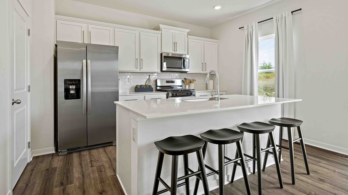 Kitchen and island with white cabinets and stainless steel appliances.