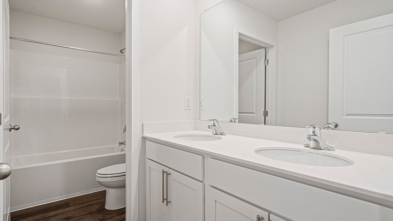 Bathroom with double sinks, white cabinets, and shower/tub combo.