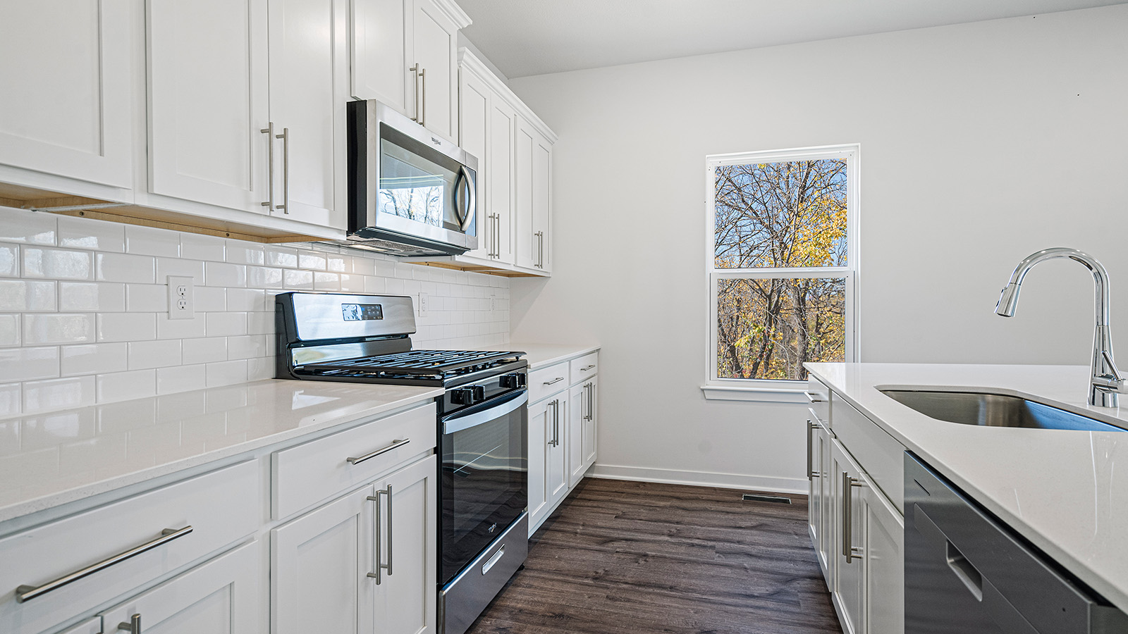 Kitchen and island with white cabinets and stainless steel appliances.