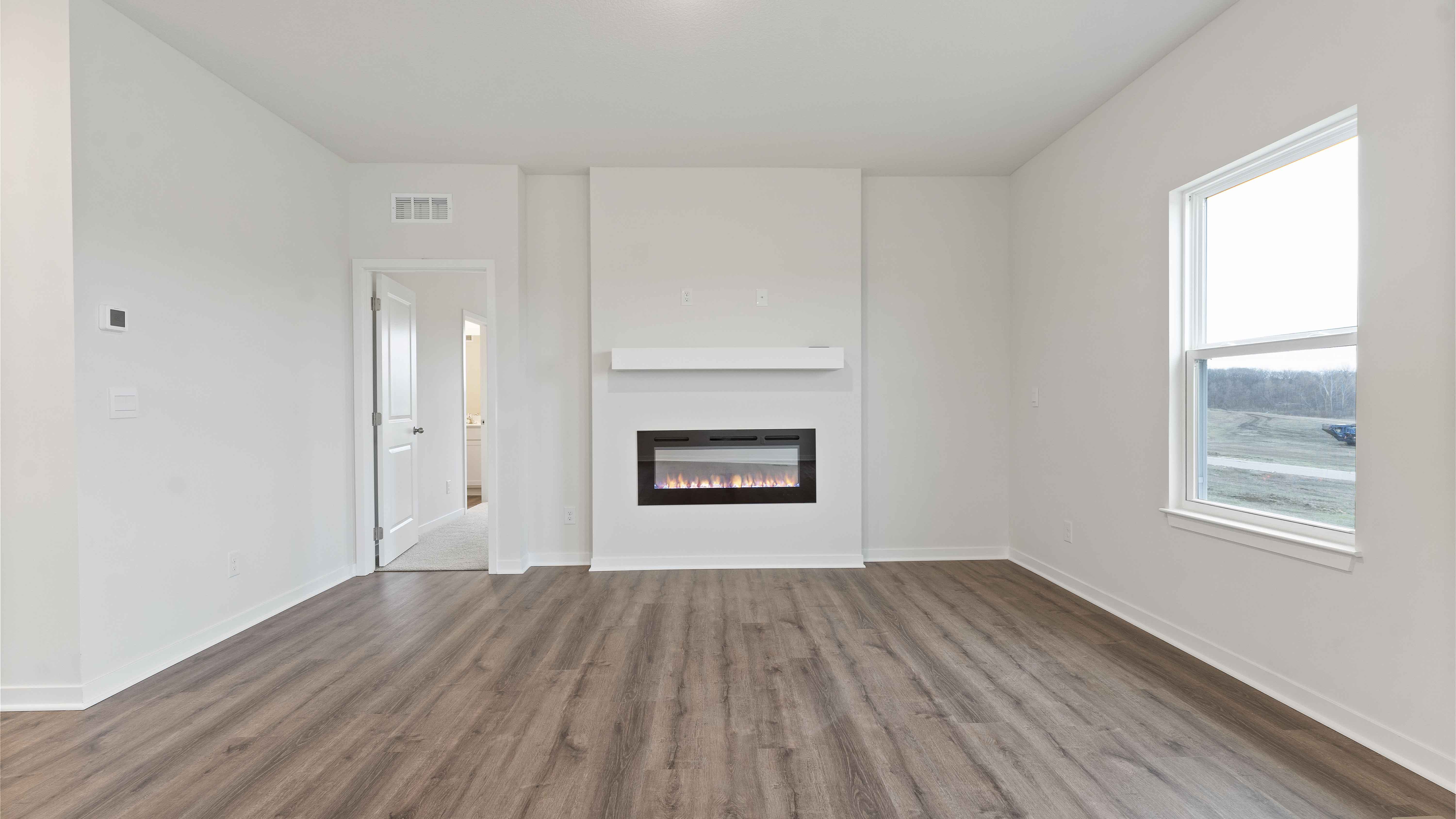 Living room with electric fireplace and two large windows, beside kitchen and dining area