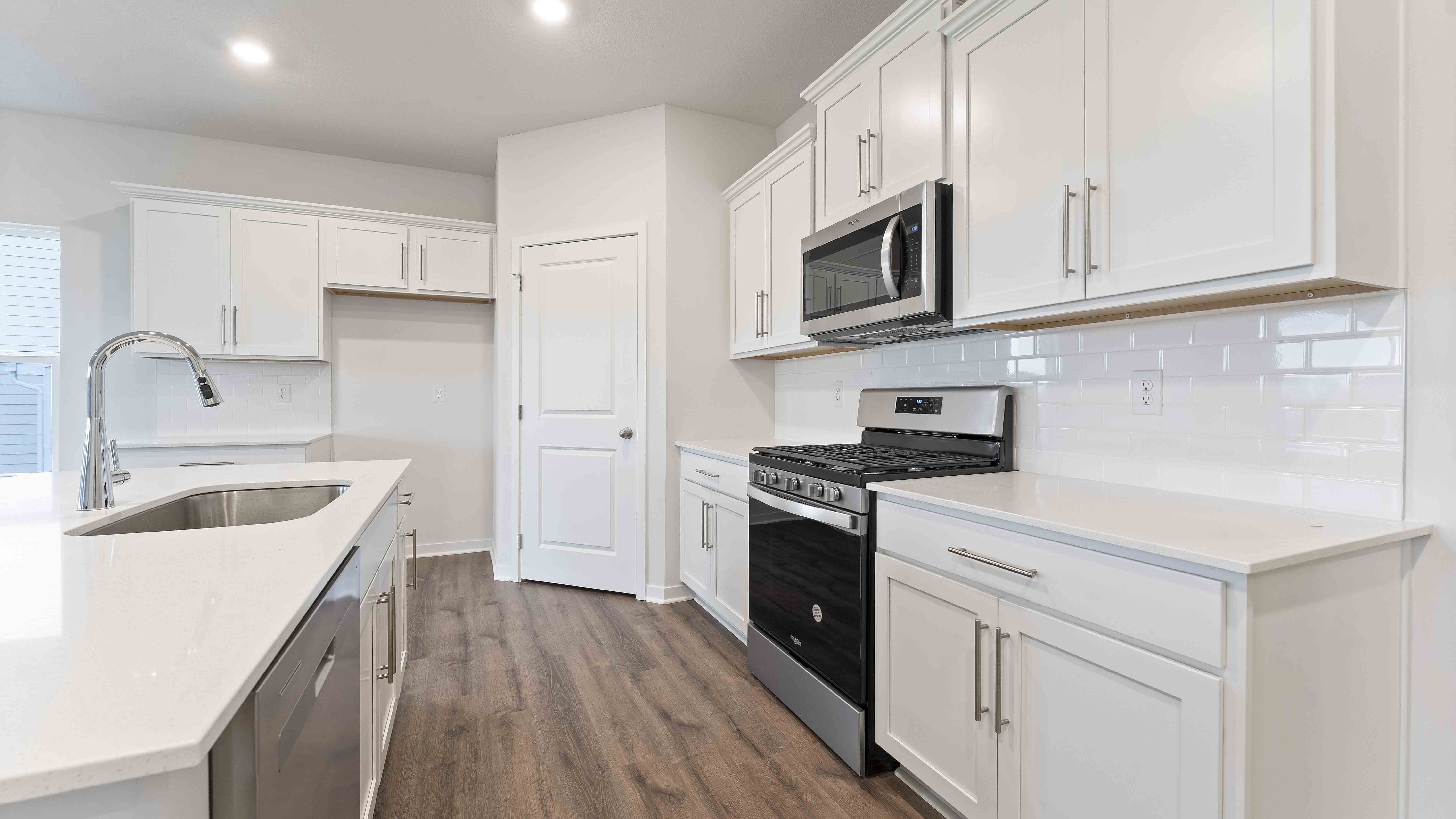 Kitchen and island with white cabinets, subway tile backsplash and stainless steel appliances