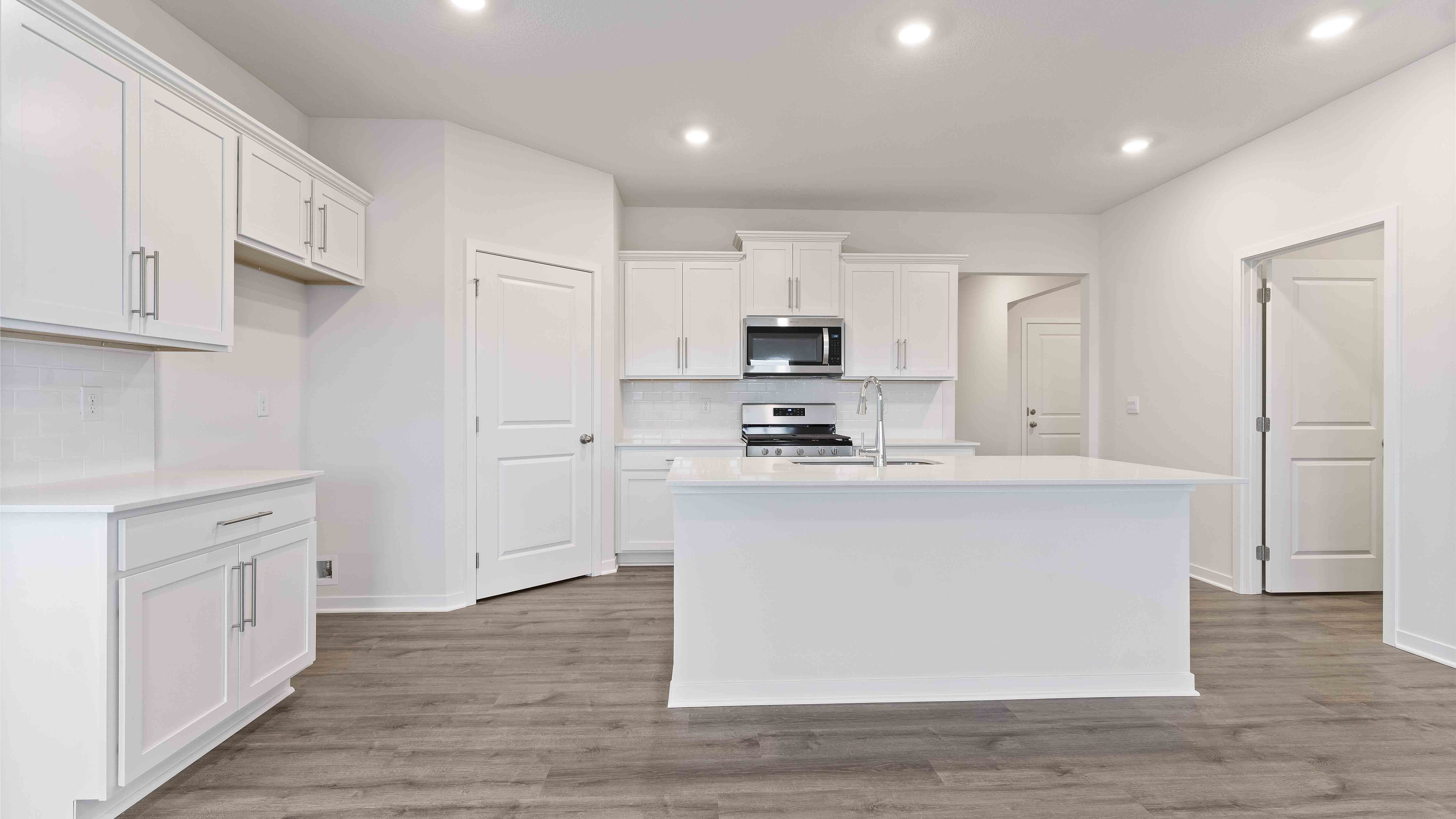 Kitchen and island with white cabinets, subway tile backsplash and stainless steel appliances