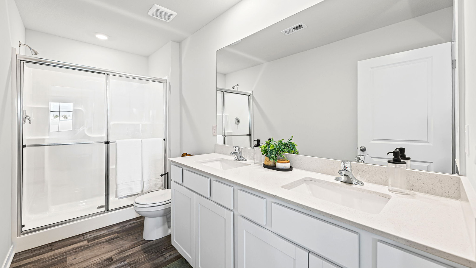 Primary bathroom with double sink vanity, standing glass door shower