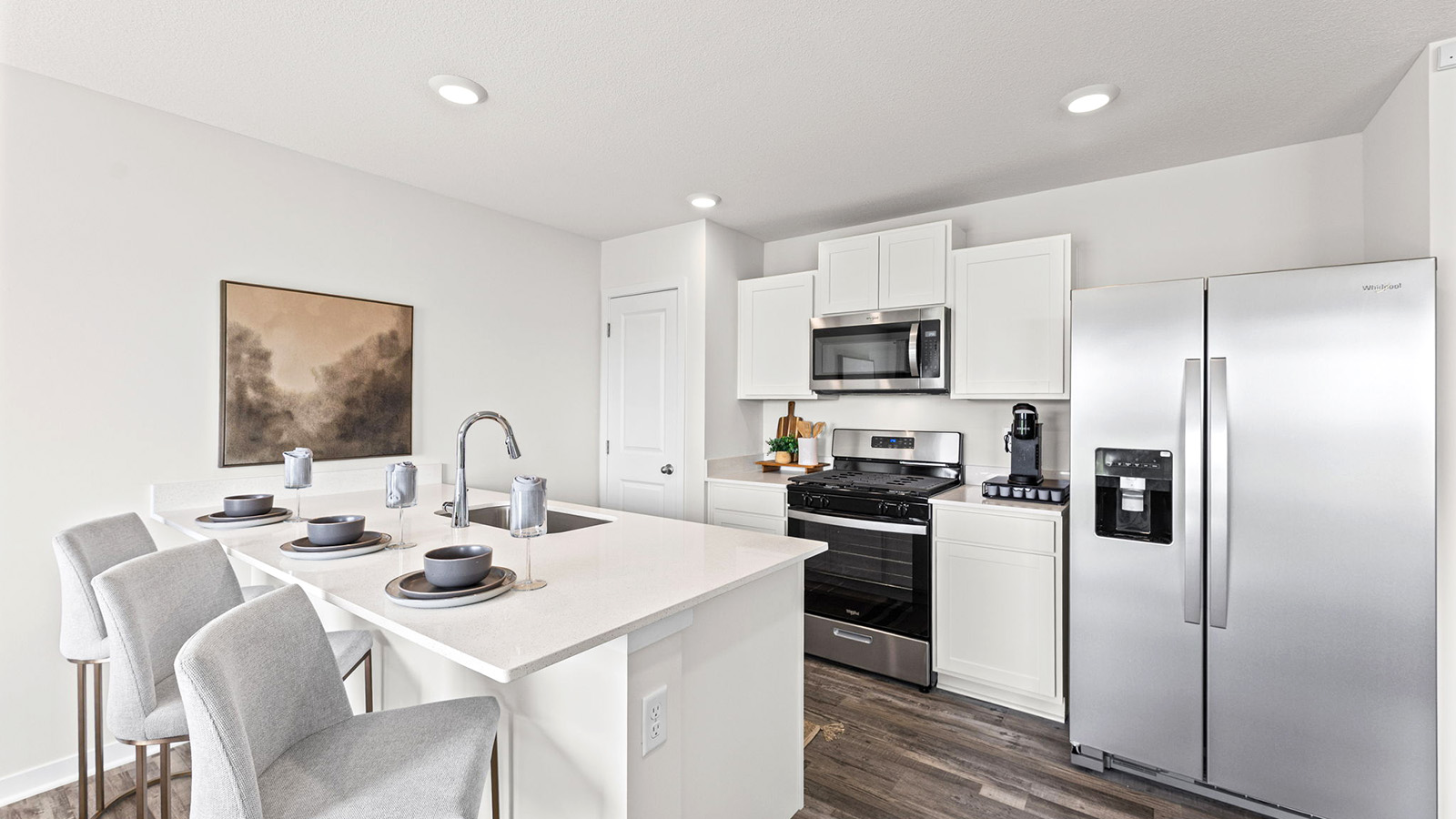 Open-concept kitchen with white counters and cabinets, and stainless steel appliances