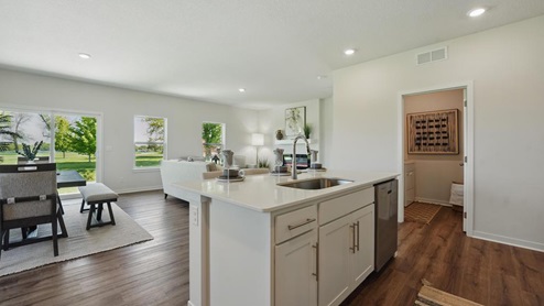 Open concept kitchen with large island, white cabinets and countertops, and stainless steel appliances