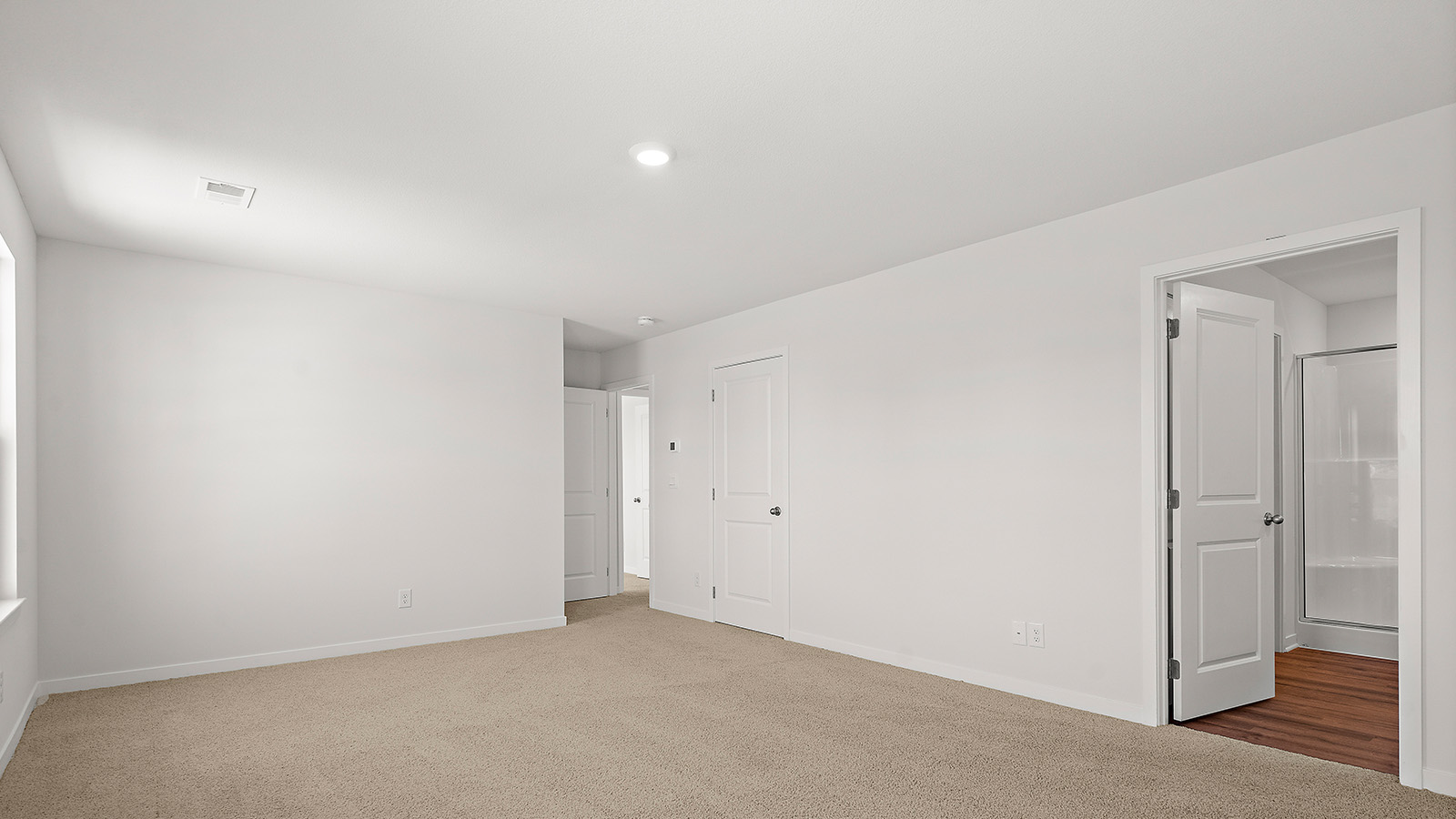 Carpeted primary bedroom with large windows and seating area. New Homes in Kansas City, Missouri