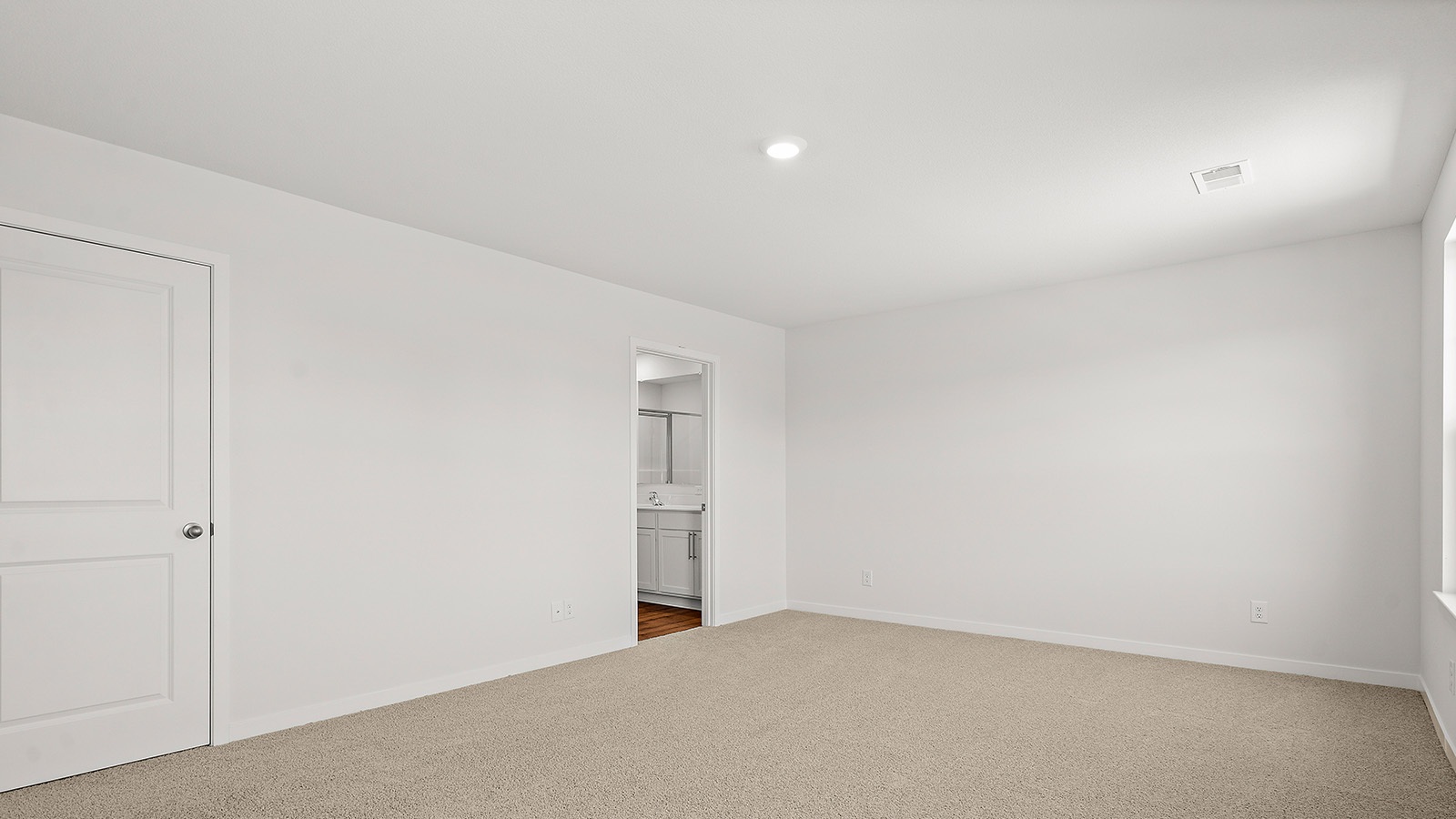 Carpeted primary bedroom with large windows and seating area. New Homes in Kansas City, Missouri