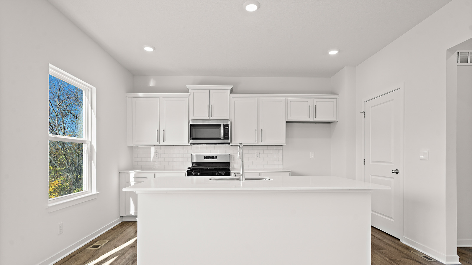 Kitchen and island with white cabinets and stainless steel appliances. New Homes in Kansas City, Missouri