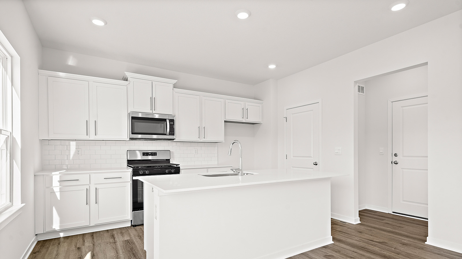 Kitchen and island with white cabinets and stainless steel appliances. New Homes in Kansas City, Missouri