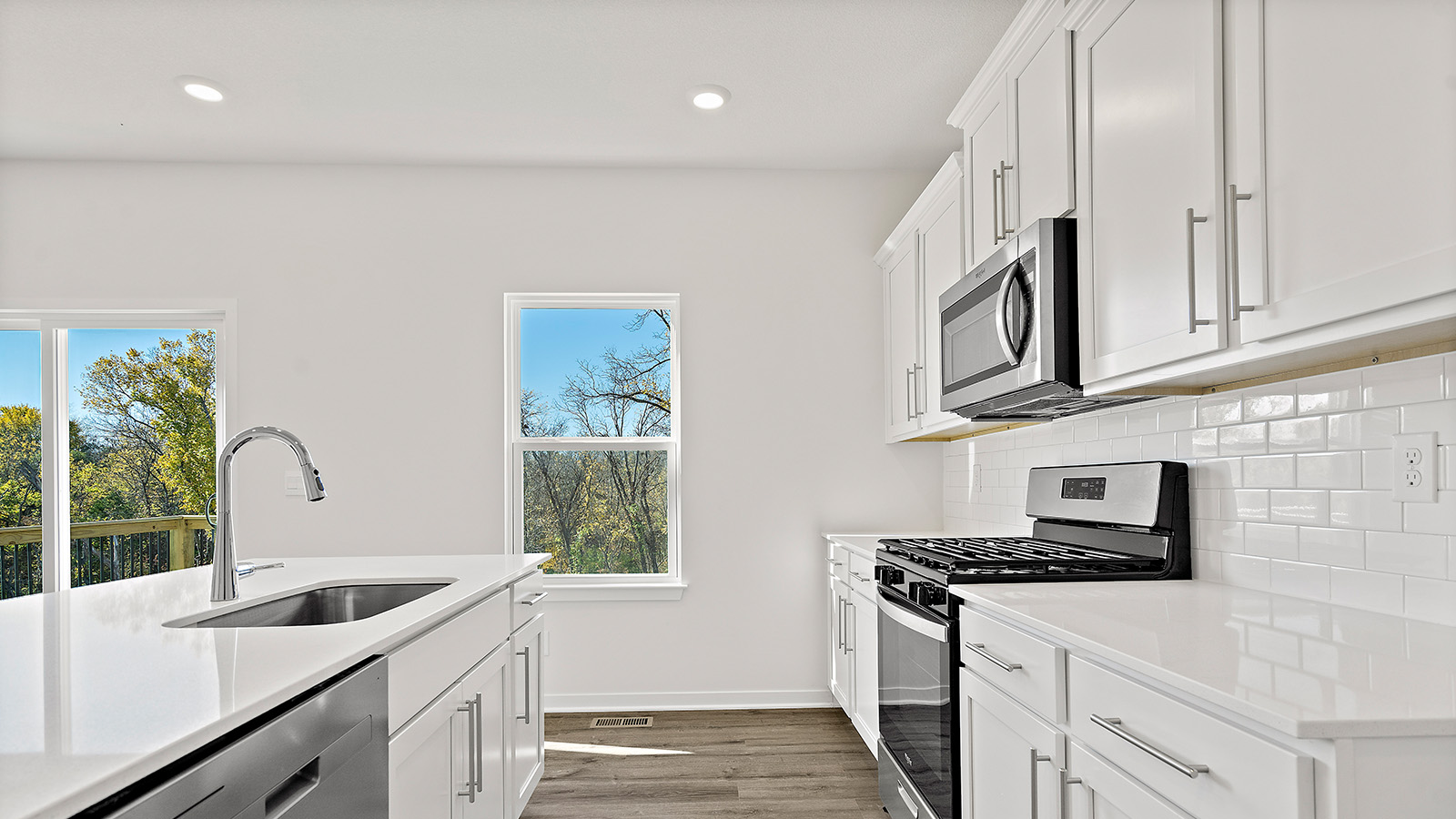Kitchen and island with white cabinets and stainless steel appliances. New Homes in Kansas City, Missouri