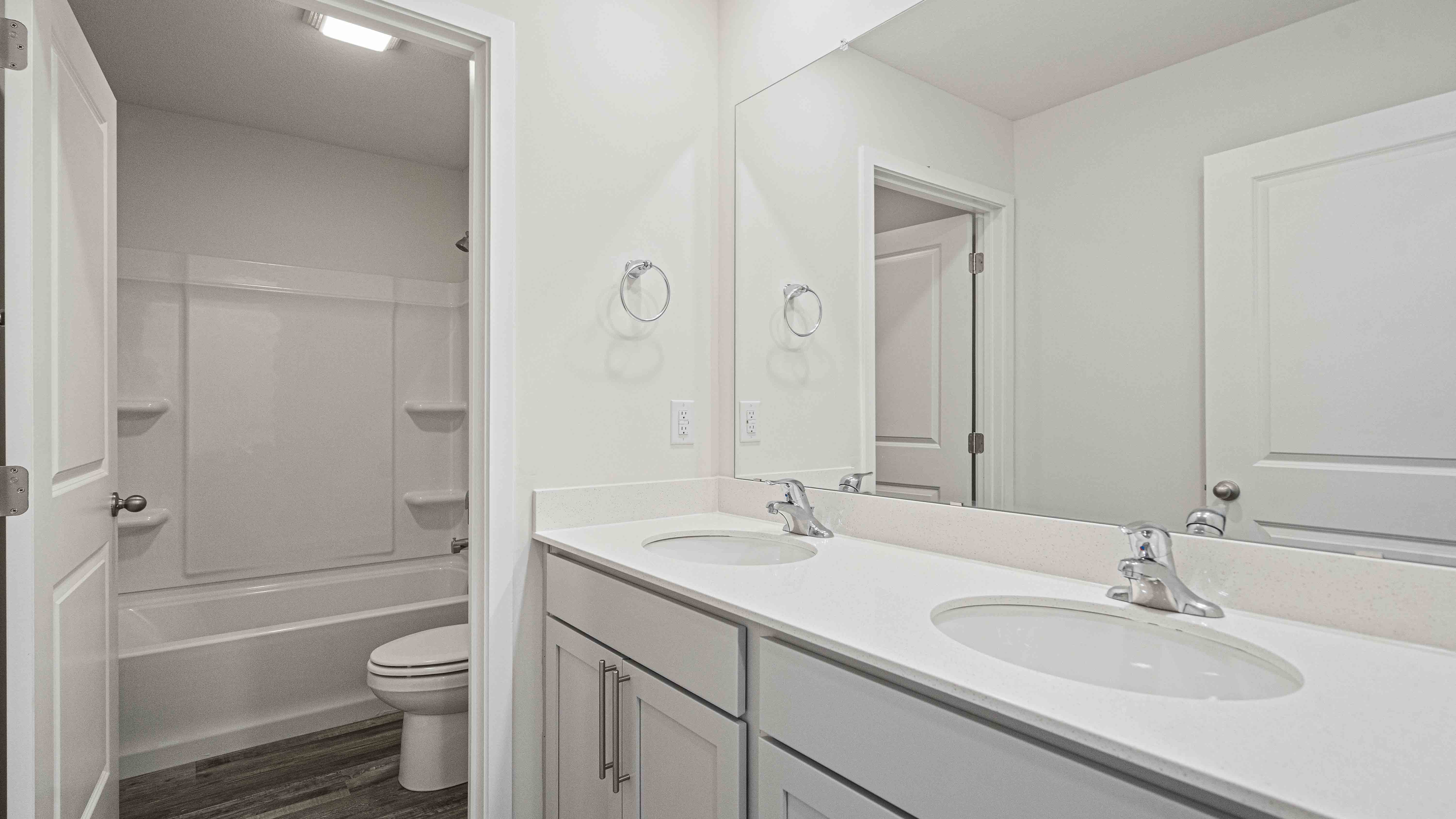 Bathroom with double sinks, white cabinets, and shower/tub combo.