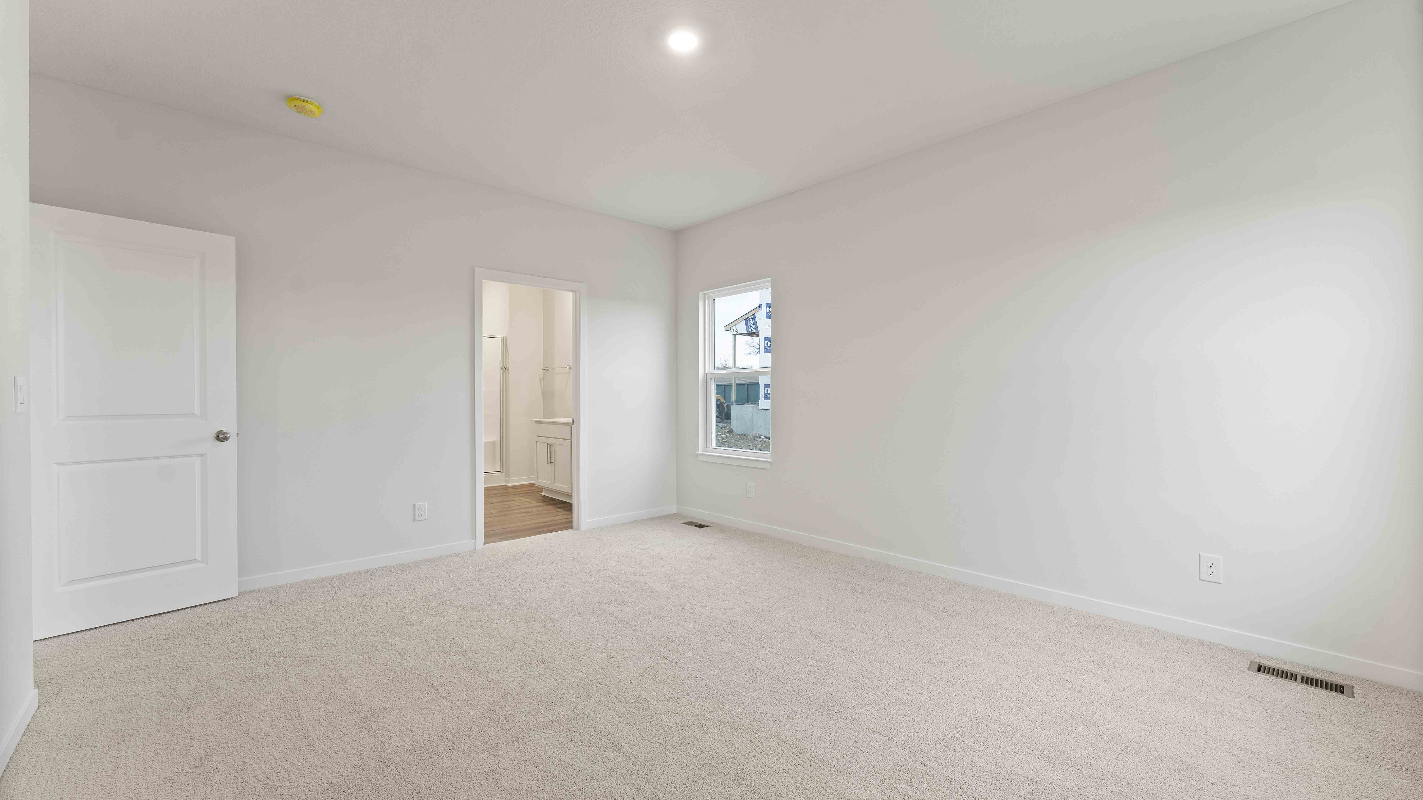 Primary carpeted bedroom with large window