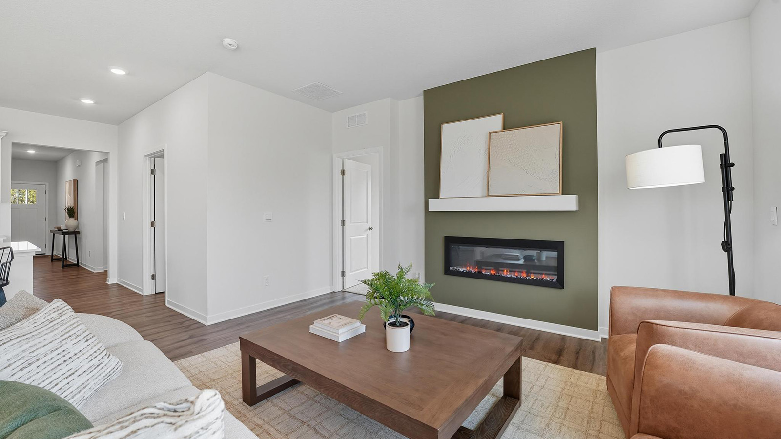 Living room with electric fireplace and two large windows, beside kitchen and dining area