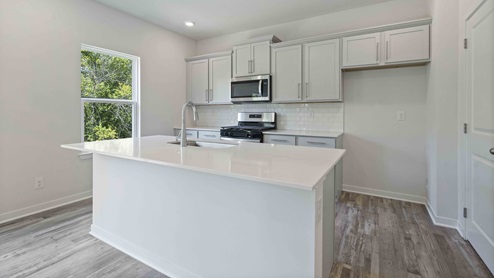 Kitchen and island with white cabinets, tile backsplash, and stainless steel appliances