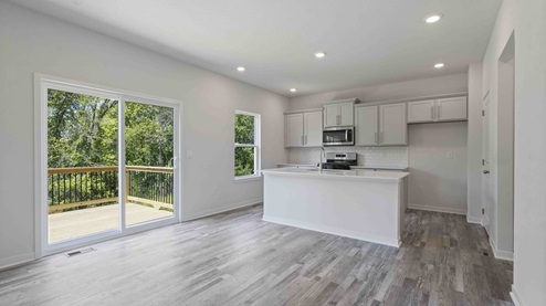 Kitchen and island with white cabinets, tile backsplash, and stainless steel appliances