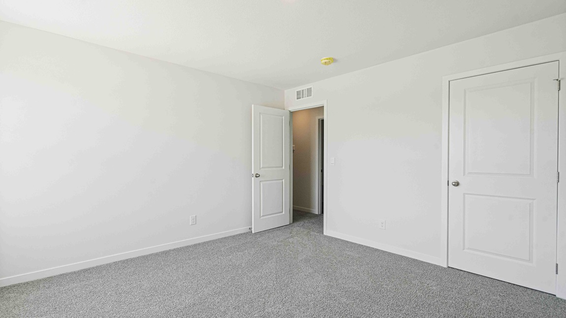 Gray carpeted bedroom with two small windows