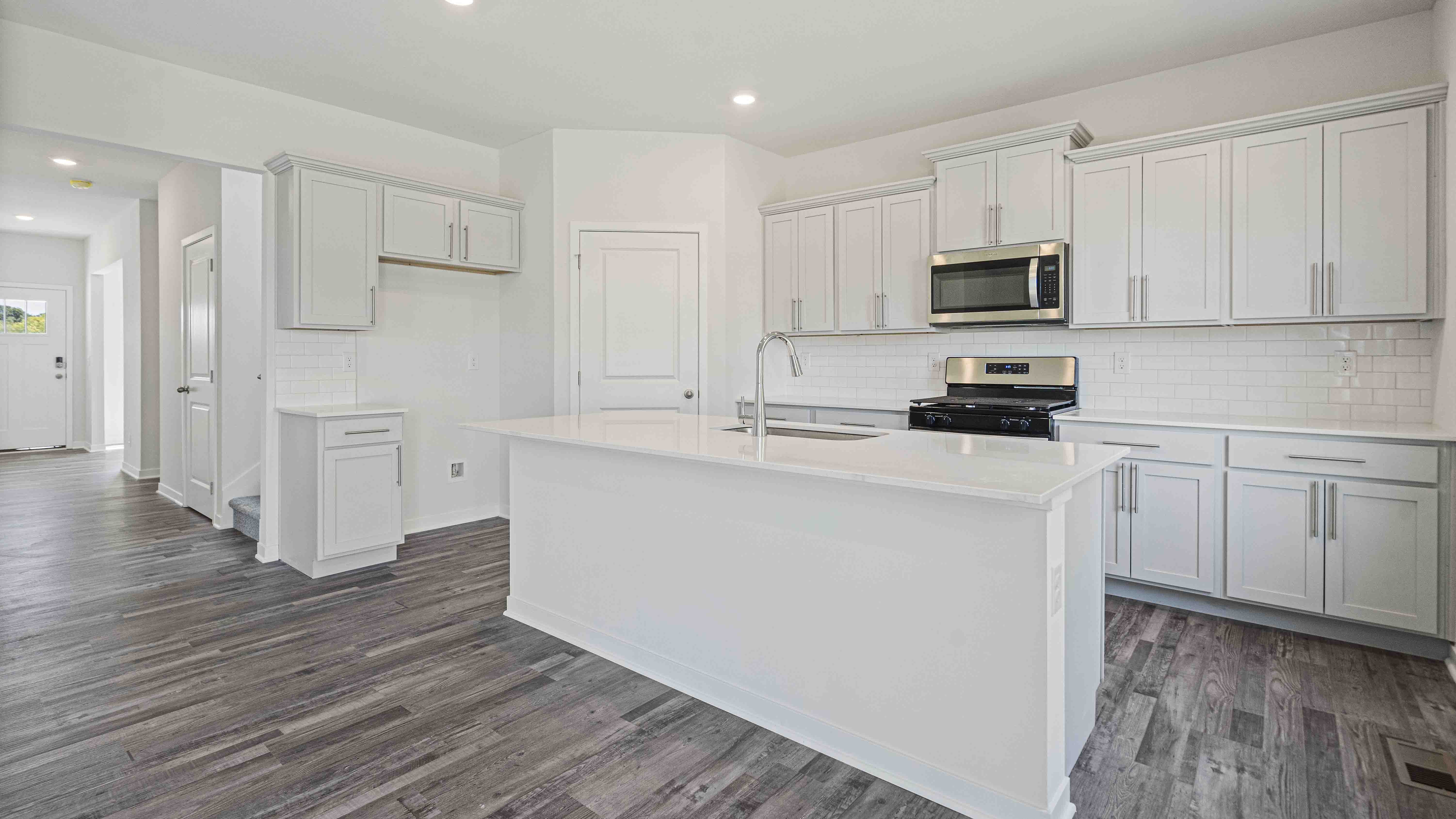 Kitchen and island with white cabinets, subway tile backsplash, and stainless steel appliances